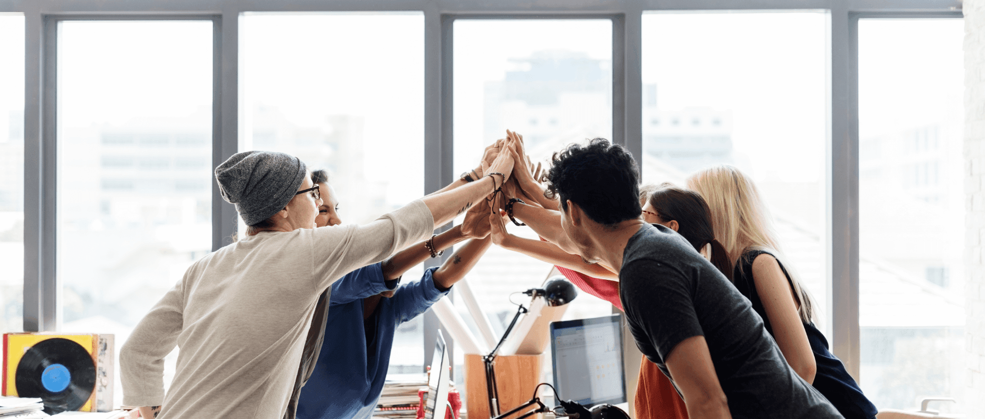 group of young people high-fiving in an office