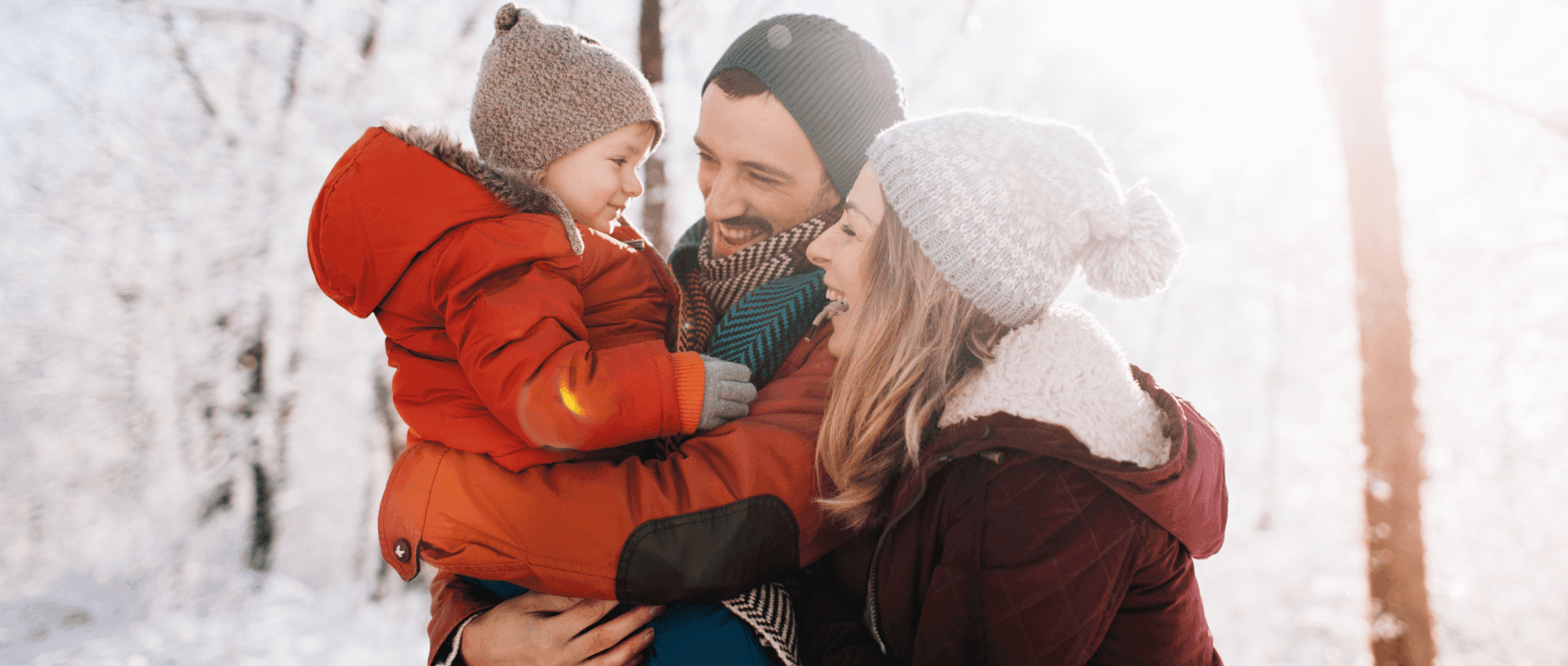 couple holding child in snowy forest