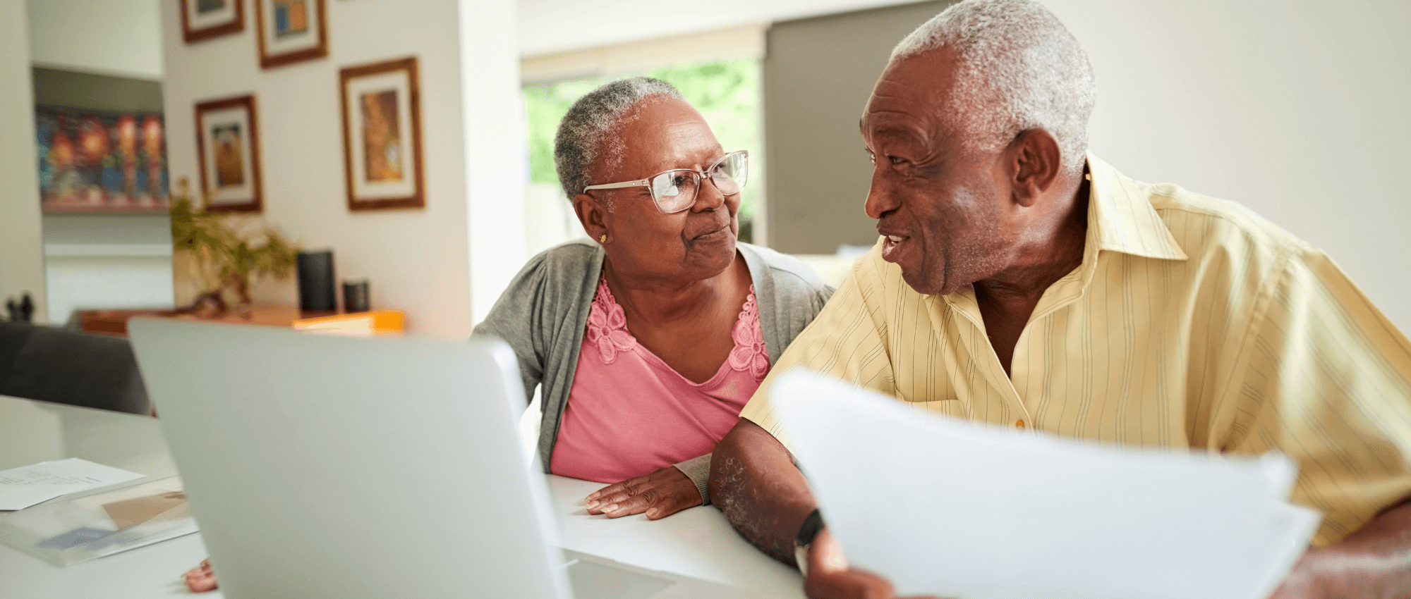 elderly couple looking at papers and laptop