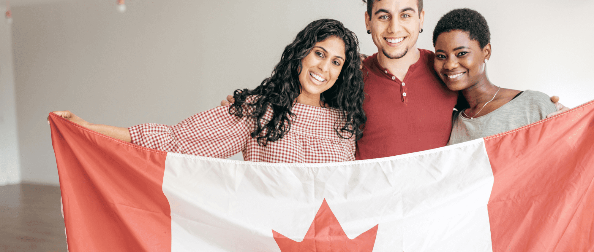 Three people holding the Canadian flag