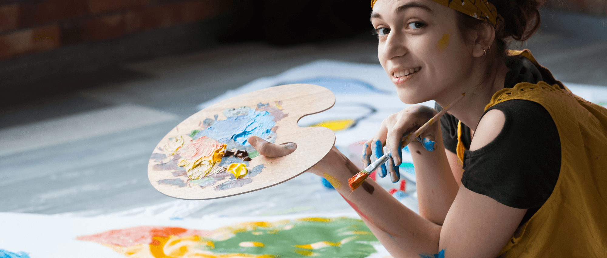 A woman holding a paint brush painting a large art piece