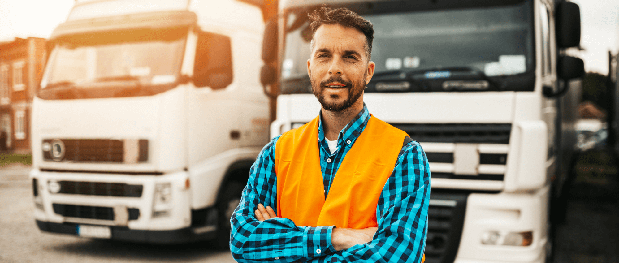 A truck driver standing in front of two trucks