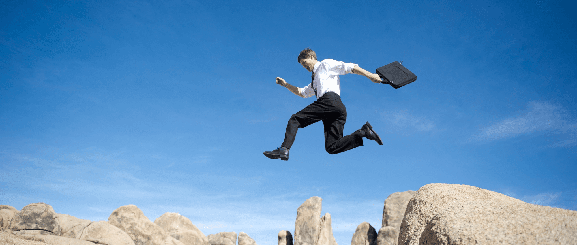 A business man jumping from one cliff to another