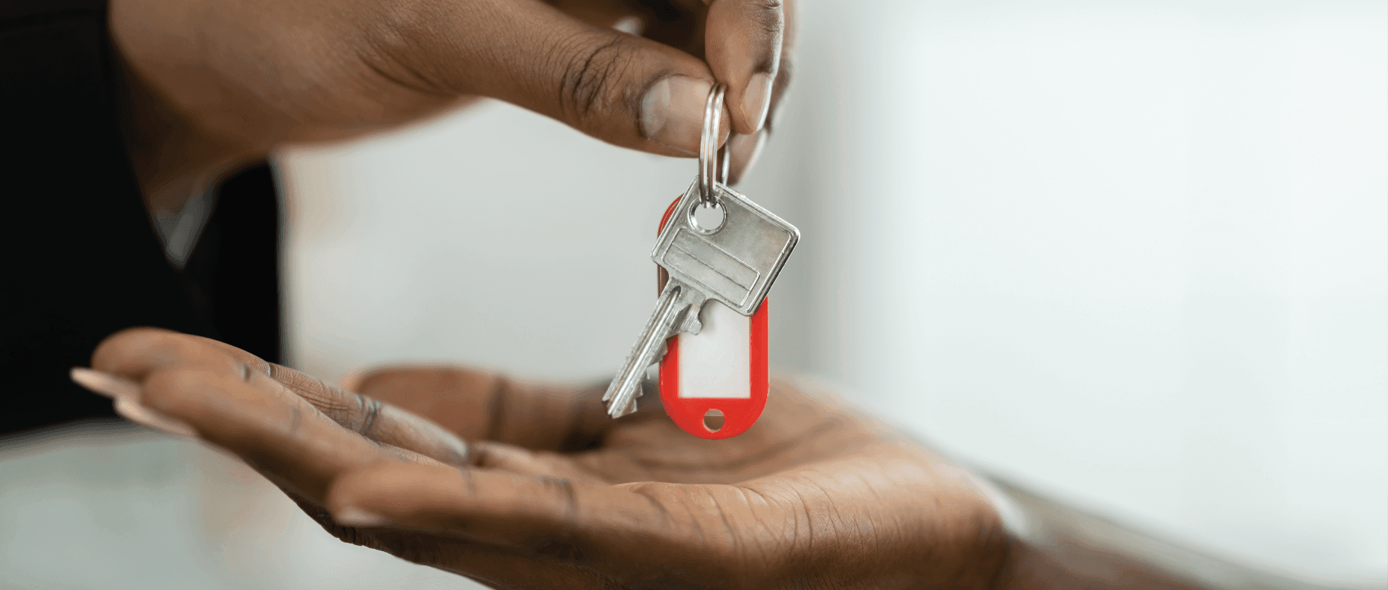 Someone giving another person keys with a red tag