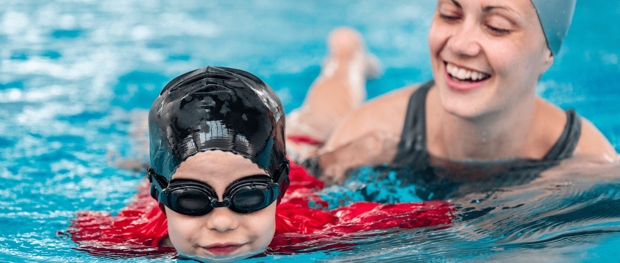 A trainer training a kid to swim