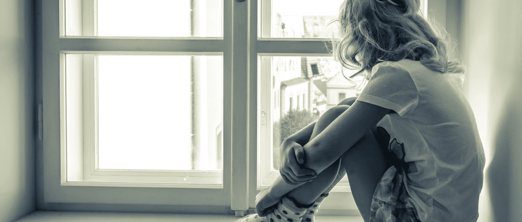 A worried child sitting alone at home