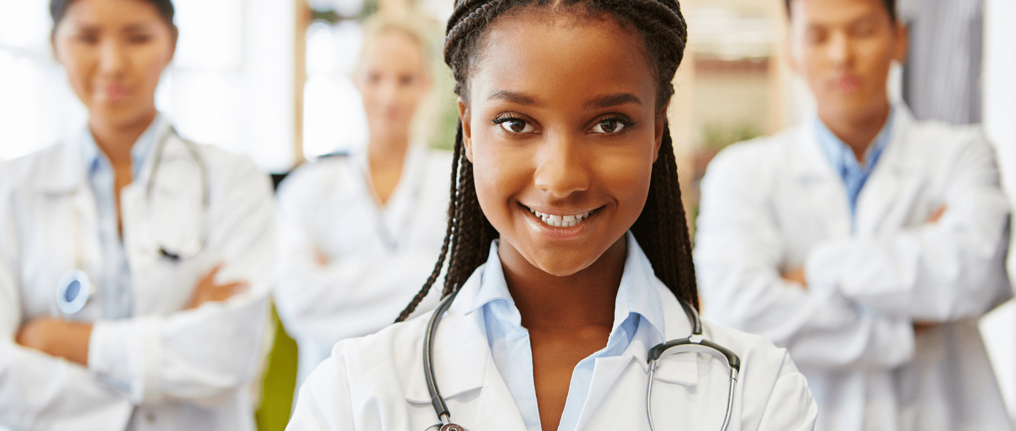 A nurse smiling at the camera with other nurses behind her