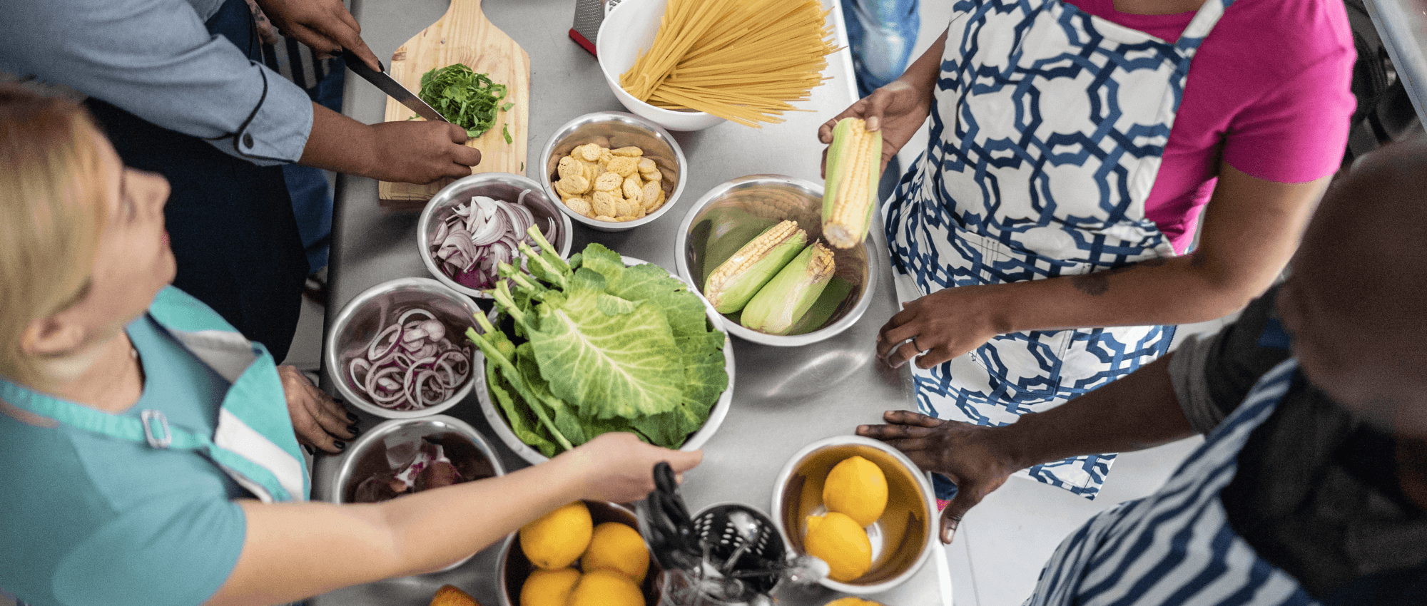 People standing around ingredients on a kitchen table
