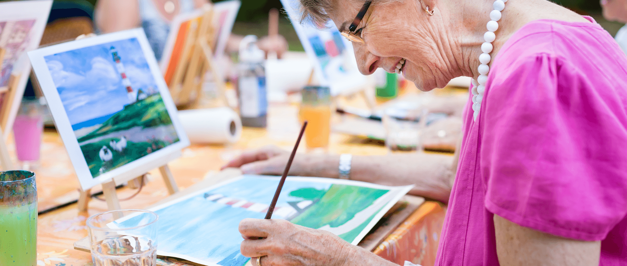 A senior painting a light house in a natural valley