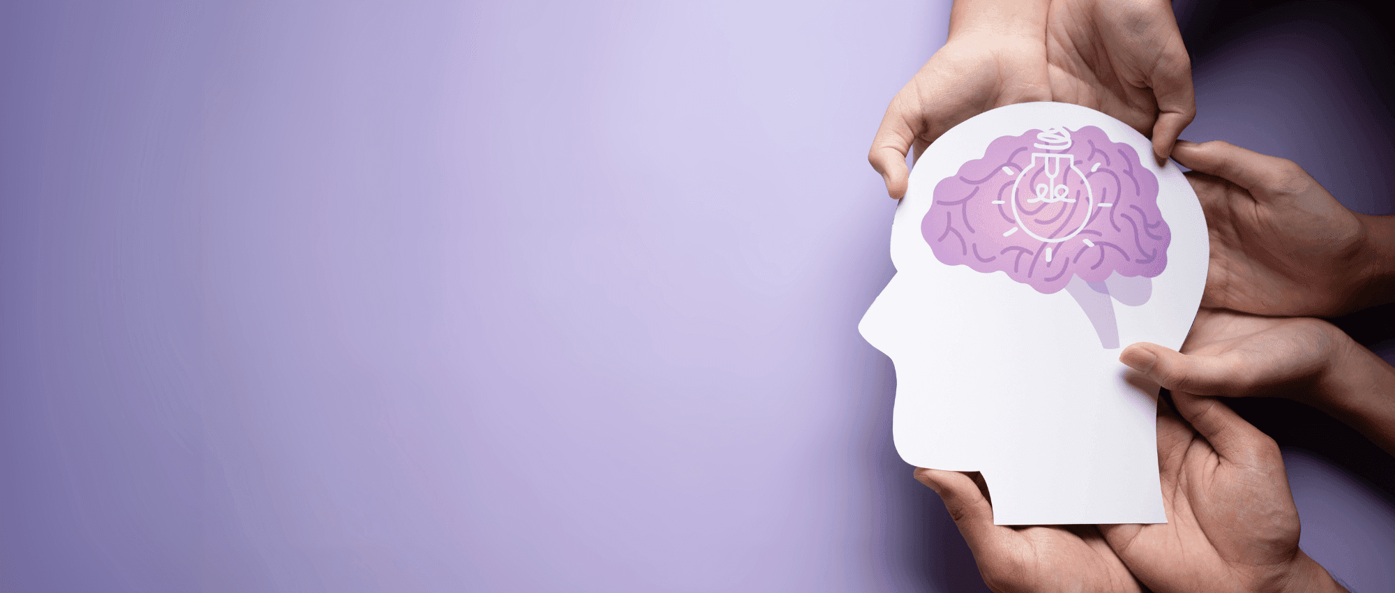 Three people holding a head papercut boardd with brain drawing inside on a light purple table